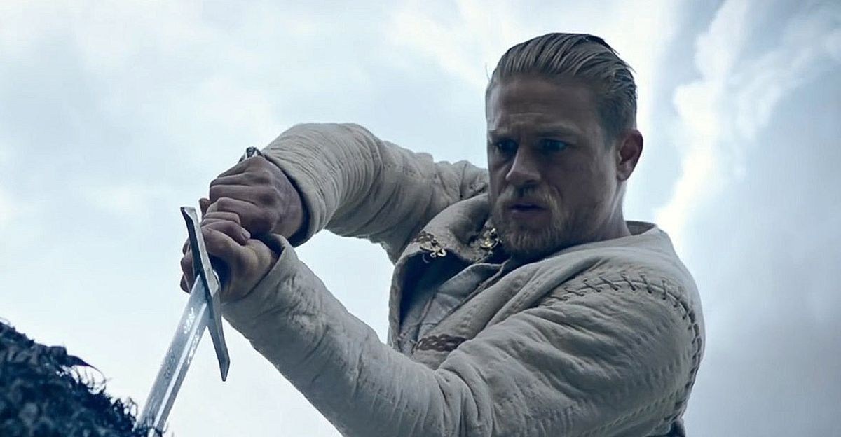 Charlie Hunnam como Arthur puxando Excalibur da pedra no rei Arthur: Legend of the Sword.