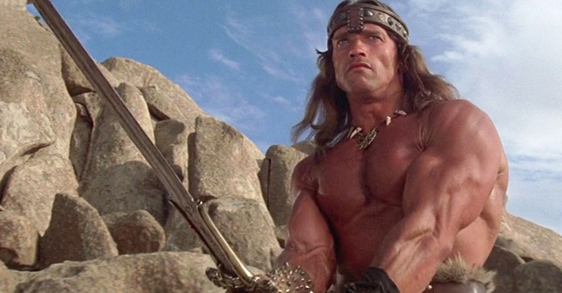 Um homem extremamente fodido empunha uma espada.