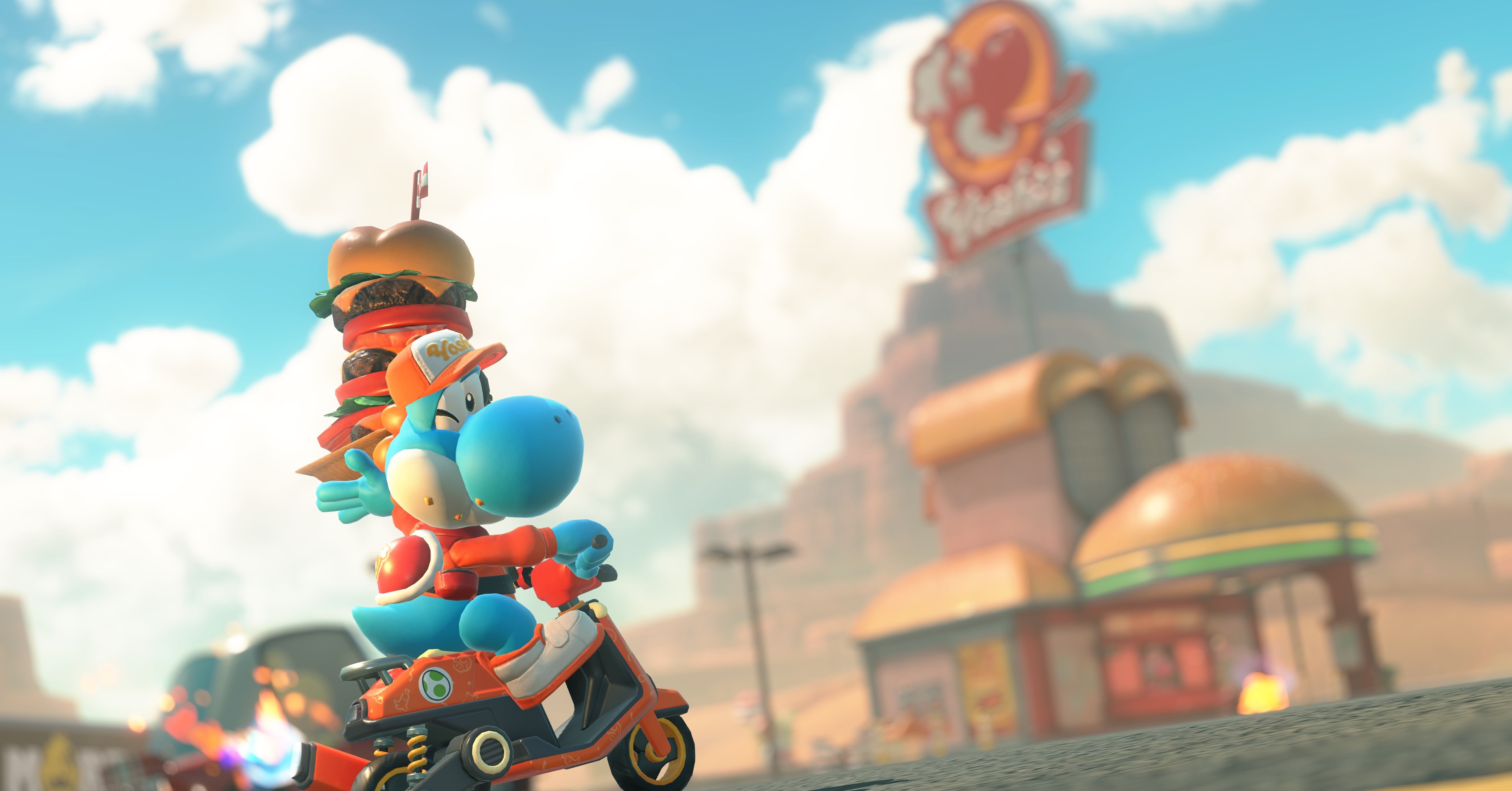 Um yoshi azul sustenta um hambúrguer empilhado do lado de fora de um drive-in de Yoshi em Mario Kart World Um yoshi azul sustenta um hambúrguer empilhado do lado de fora de um drive-in de Yoshi em Mario Kart World