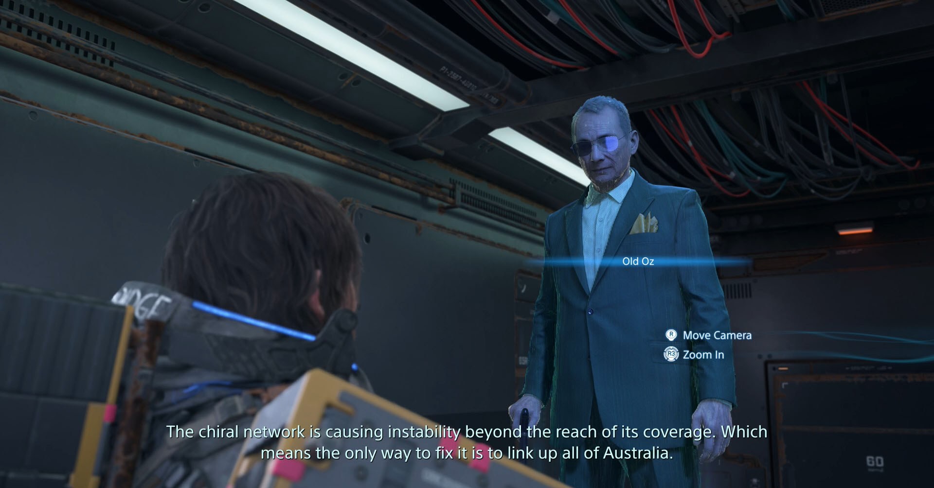 Uma captura de tela do Death Stranding 2 mostrando Sam conversando com o holograma de um velho chamado Old Oz. Uma captura de tela do Death Stranding 2 mostrando Sam conversando com o holograma de um velho chamado Old Oz.