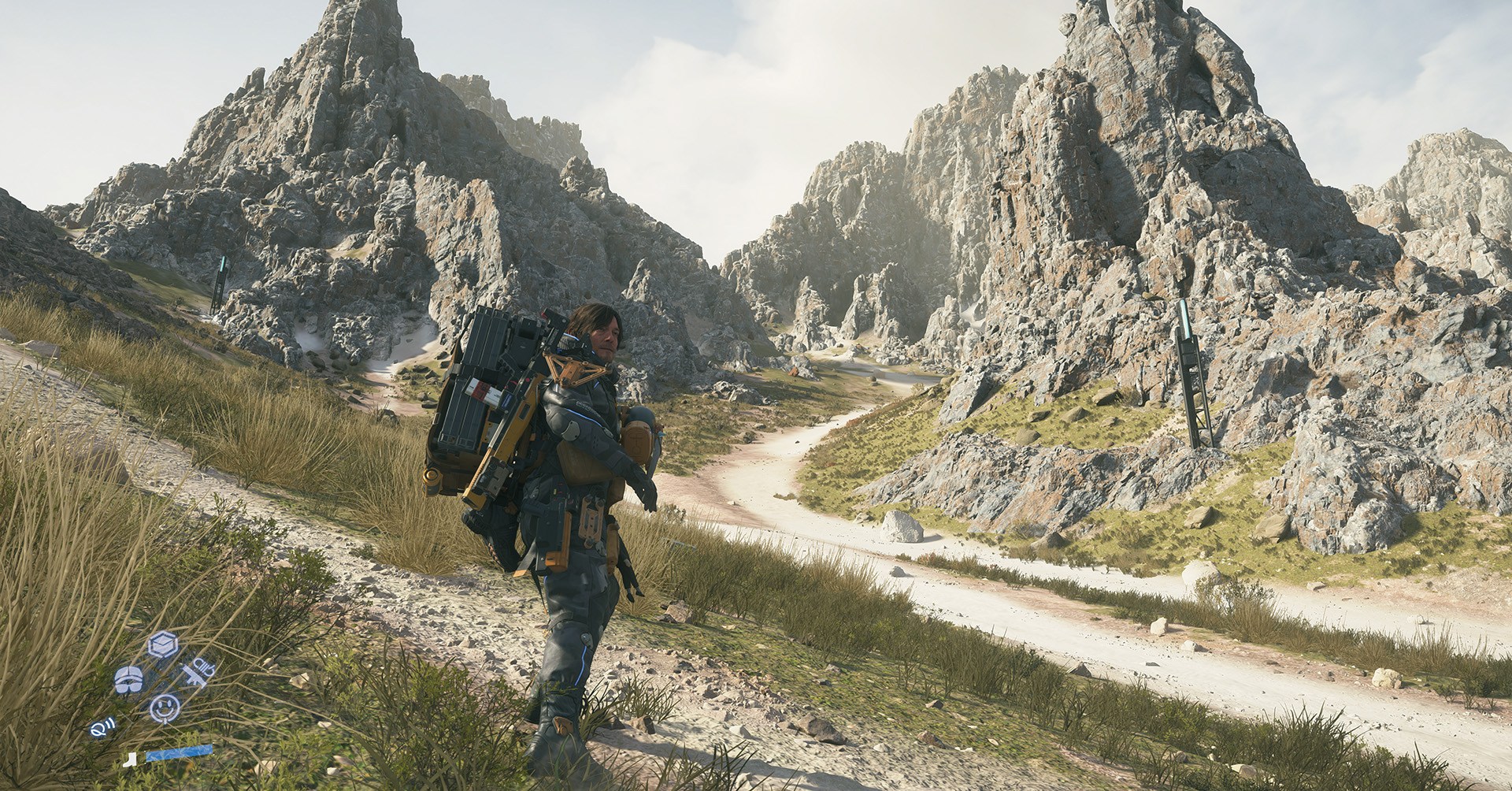 Sam Bridges está diante de uma paisagem de montanha acidentada em Death Stranding 2