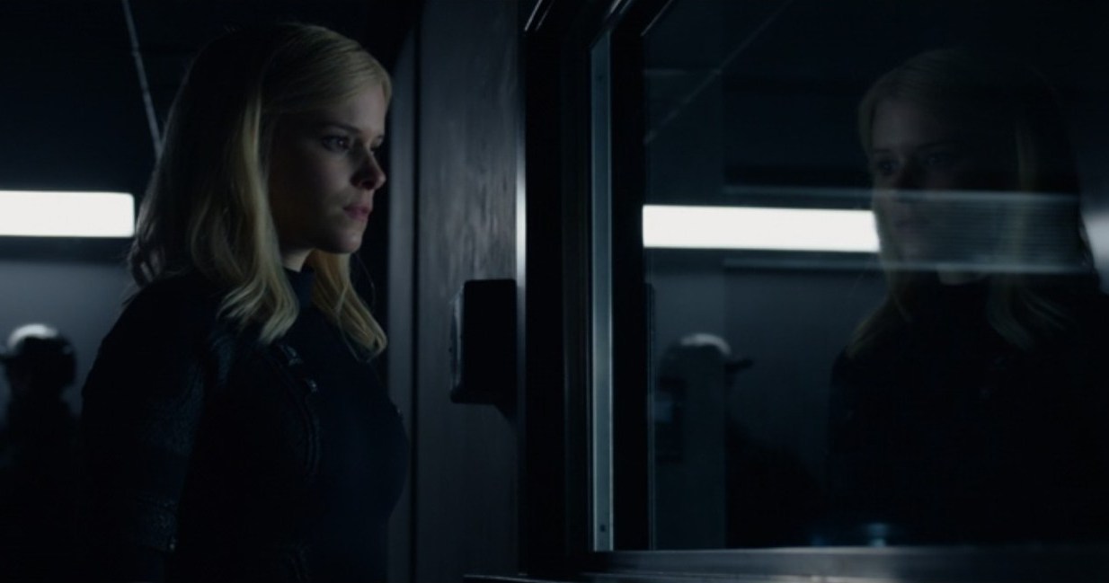Sue Storm (Kate Mara) analisa seu reflexo em uma janela de instalações militares nesta cena do Quarteto Fantástico de 2015. 