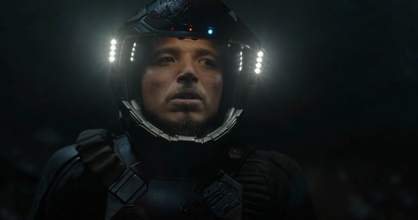 Andy (Anthony Ramos) de longa distância na escuridão usando as luzes do capacete em seu traje espacial Andy (Anthony Ramos) de longa distância na escuridão usando as luzes do capacete em seu traje espacial