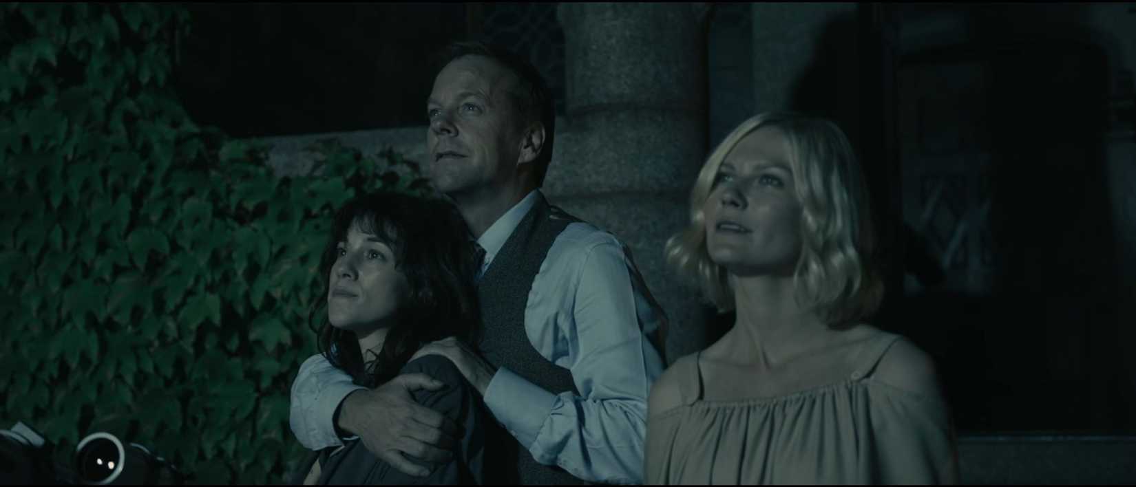 Kristen Dunst, Charlotte Gainsbourg e Kiefer Sutherland olham para o céu noturno brilhante em uma cena do filme melancolia