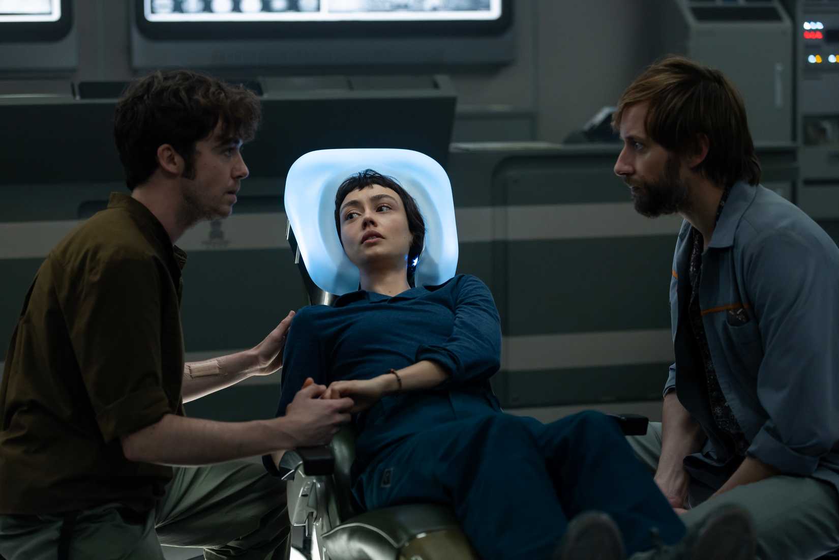 Hermit (Alex Lawther) e Arthur (David Rysdahl) ficam perto de Wendy (Sydney Chandler) enquanto ela se deita em uma cama médica parecendo preocupada e segurando a mão de Hermit em Alien: Terra