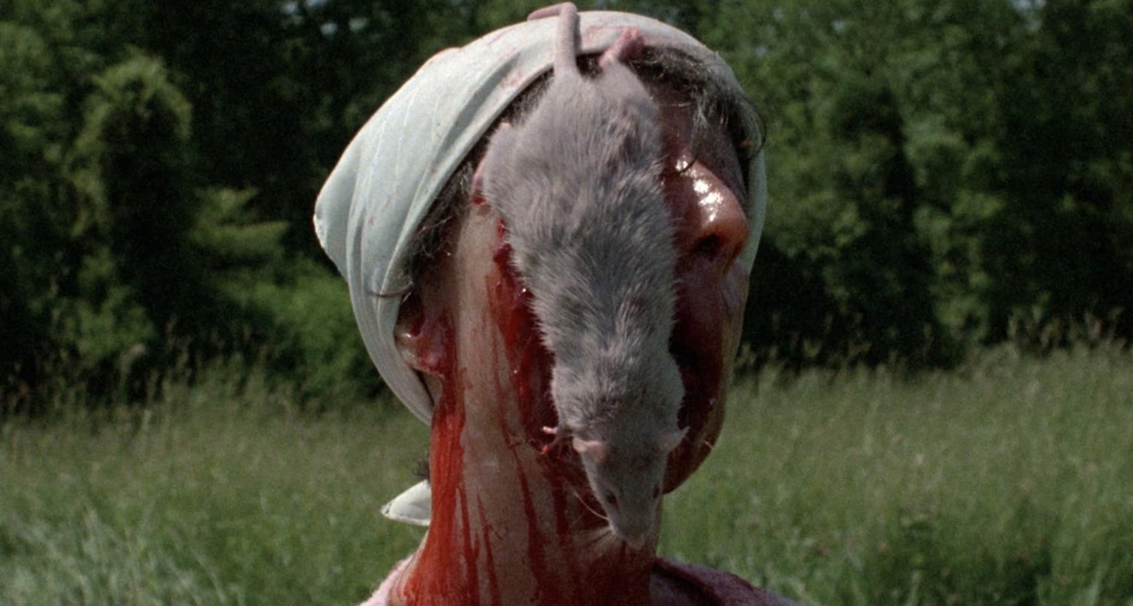 Um tiro de Cuidado! Crianças em brincadeira, com um cadáver com sangue sentado na vertical, com um rato vivo pendurado em seu rosto