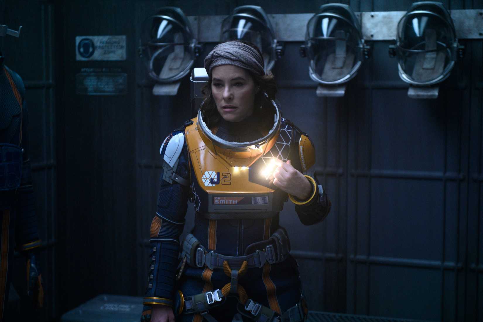 Parker Posey em um traje espacial sem capacete parecendo assustado em Lost in Space temporada 2