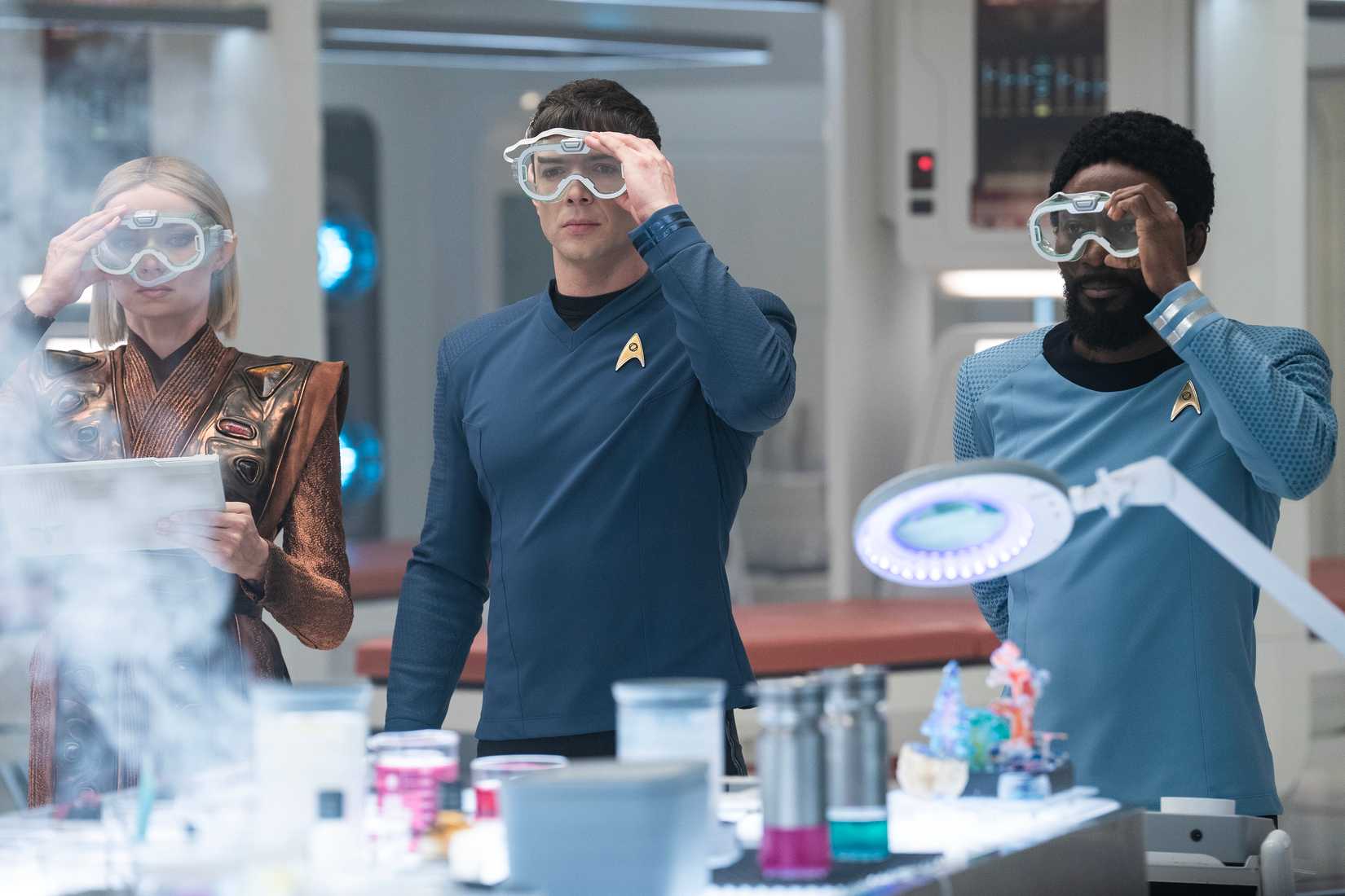 Jess Bush como Chapel, Ethan Peck como Spock e Babs Oluusanmokun como Dr. M'Benga Realizar um experimento científico em Star Trek: Strange New Worlds