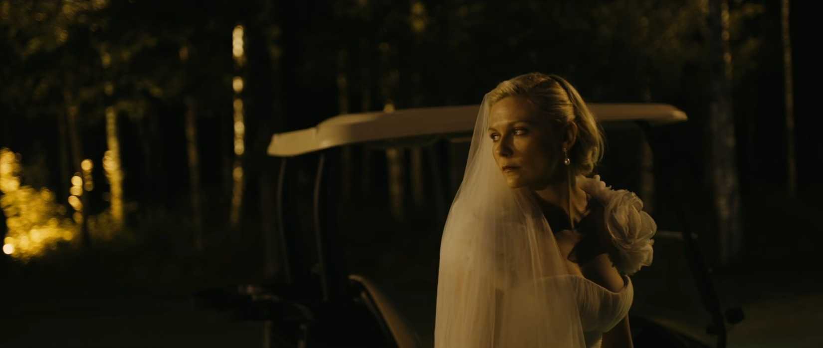 Kirsten Dunst parece profundamente infeliz em um vestido de noiva em uma cena noturna do filme melancolia