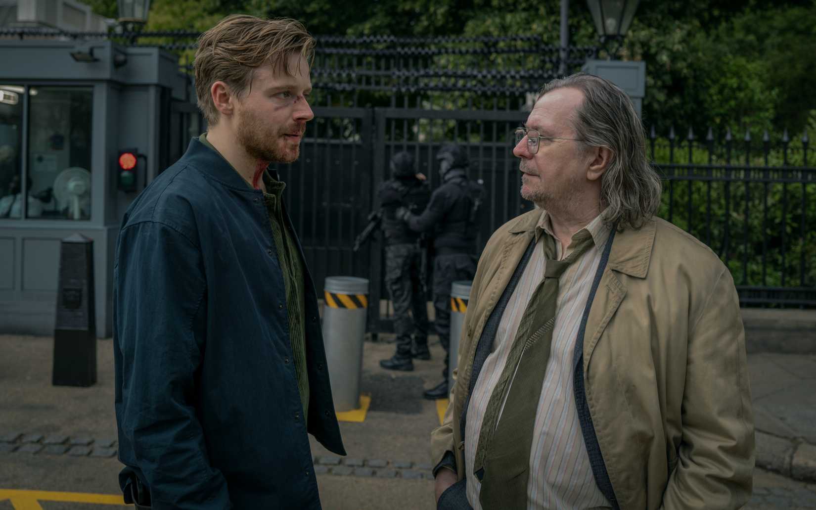 Jack Lowden e Gary Oldman conversam na frente de uma área segura em cavalos lentos