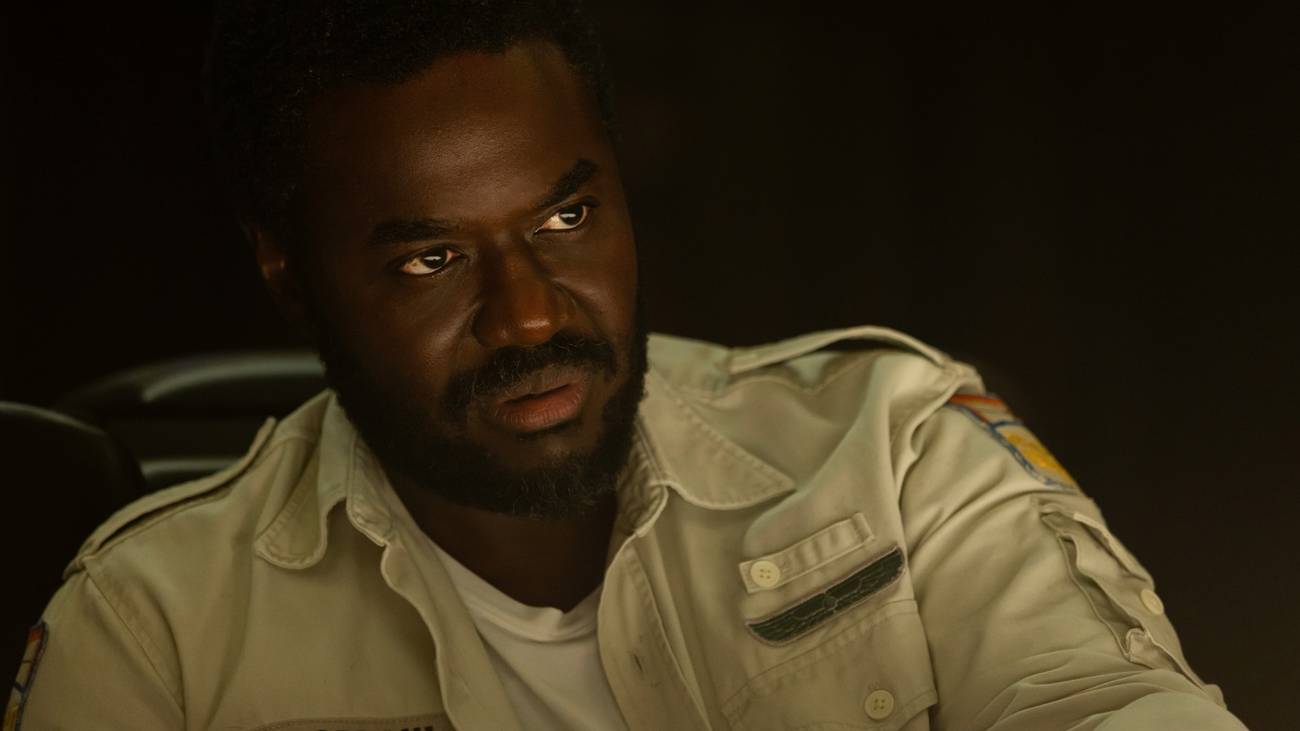 Morrow (Babou Ceesay) olha para algo fora da tela.