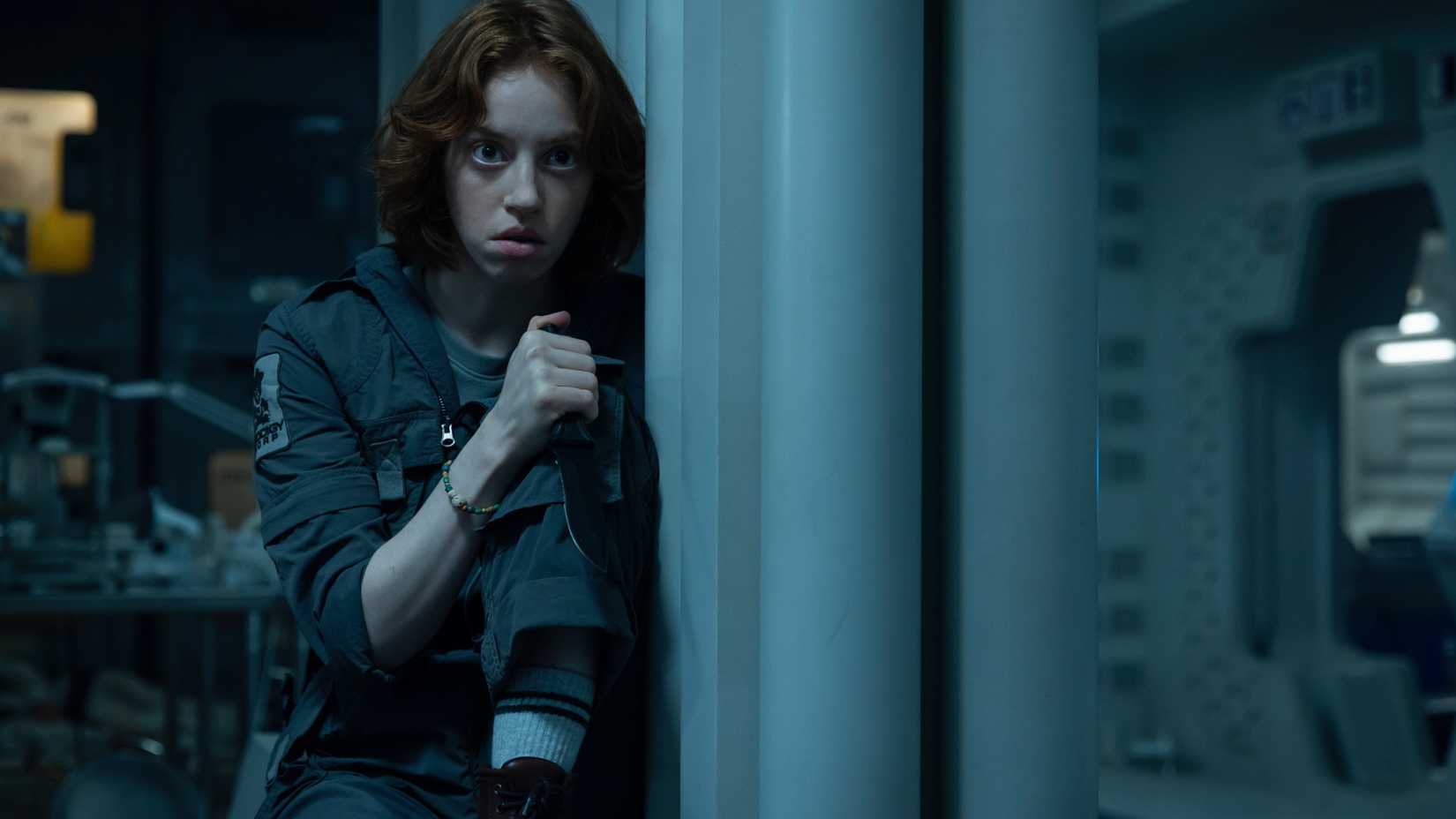 Nibs (Lily Newmark) se esconde em um canto segurando uma faca após seu primeiro encontro com a espécie 64.