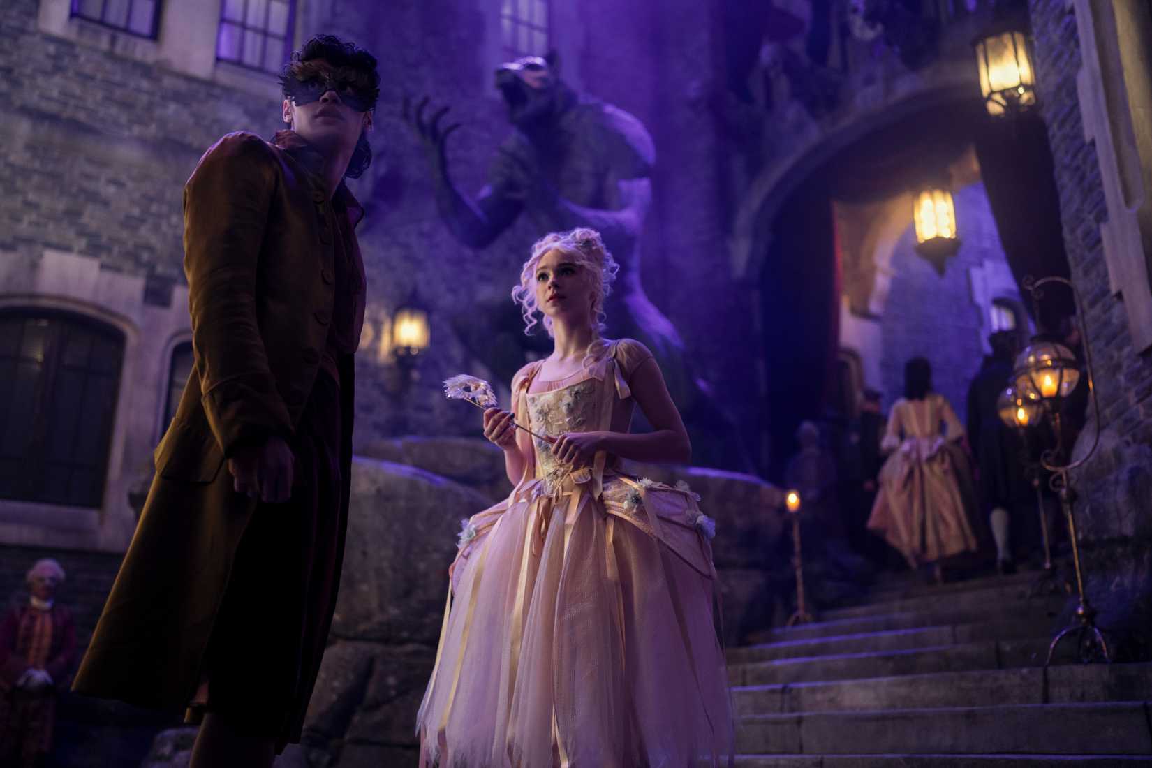 Imagem com Enid Sinclair e Bruno de quarta -feira. Ambos estão em vestido extravagante, com Bruno usando uma máscara.