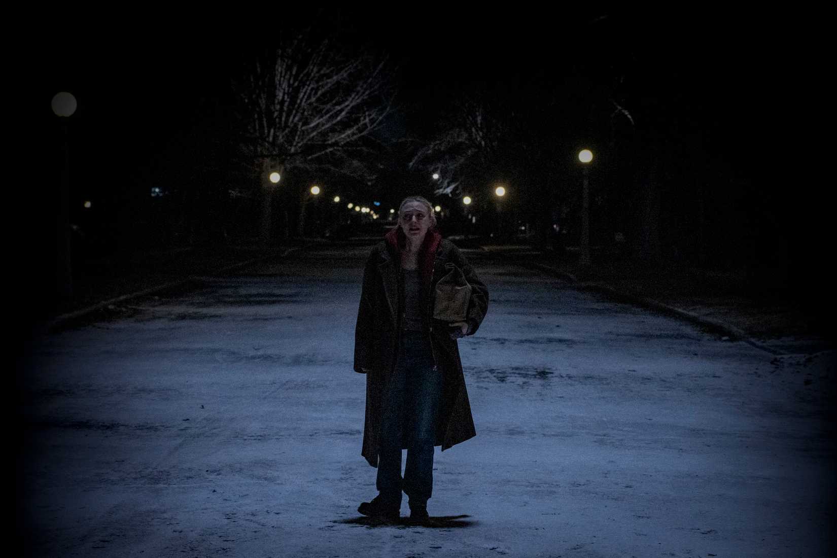 Polly (Dakota Fanning) chora no meio de uma rua suburbana coberta de neve à noite, com uma caixa em um grande saco de papel marrom debaixo do braço, em Vicious.