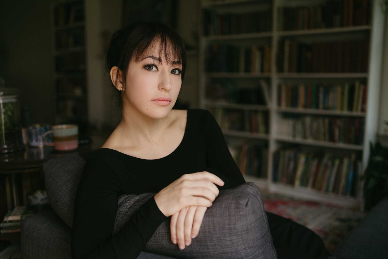 SenLinYu posa em frente a uma estante