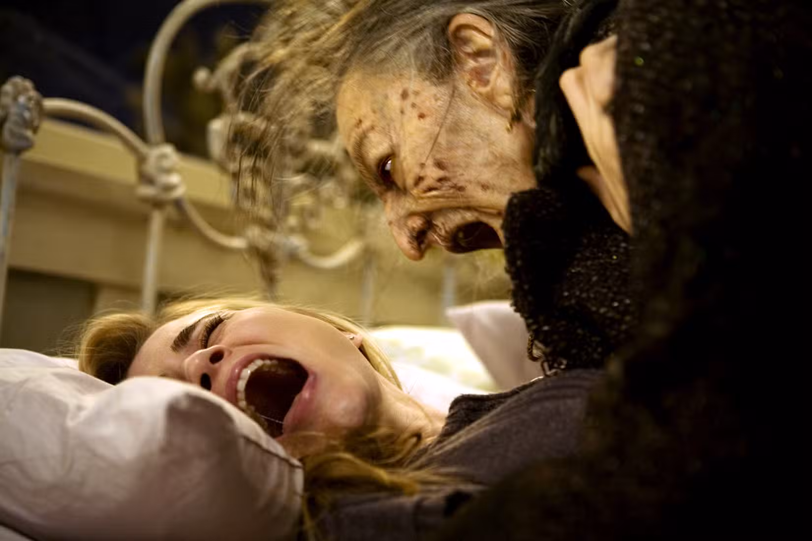 Uma senhora idosa com cortes no rosto tenta morder Alison Lohman em Drag Me to Hell