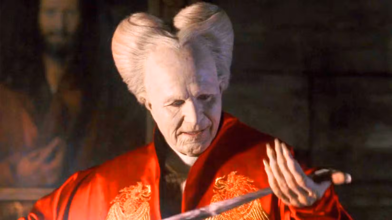 Gary Oldman como Drácula em um manto vermelho, maquiagem branca e peruca branca em Drácula de Francis Ford Coppola