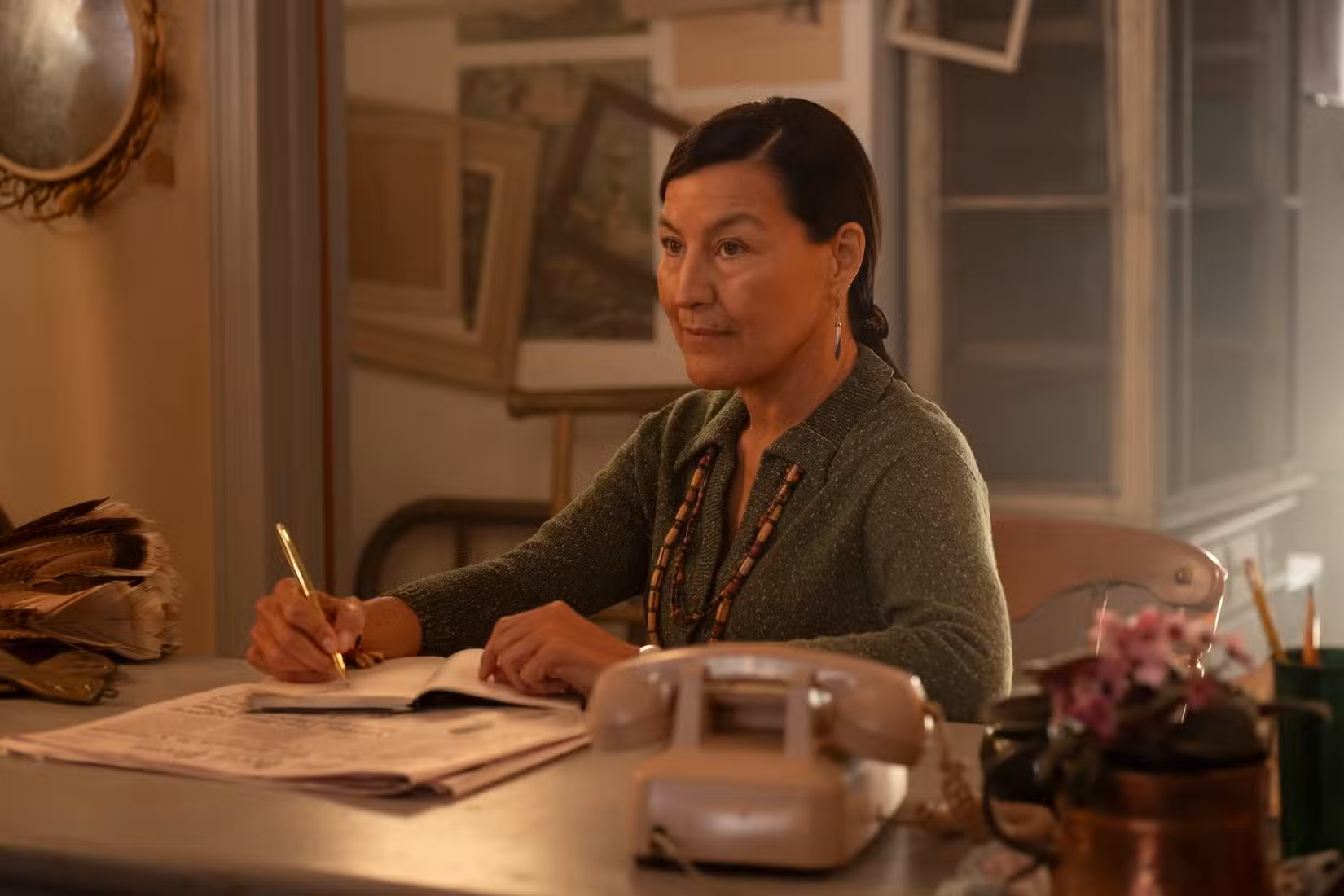 Kimberly Guerrero como Rose, sentada em uma mesa escrevendo algo de It: Bem-vindo a Derry