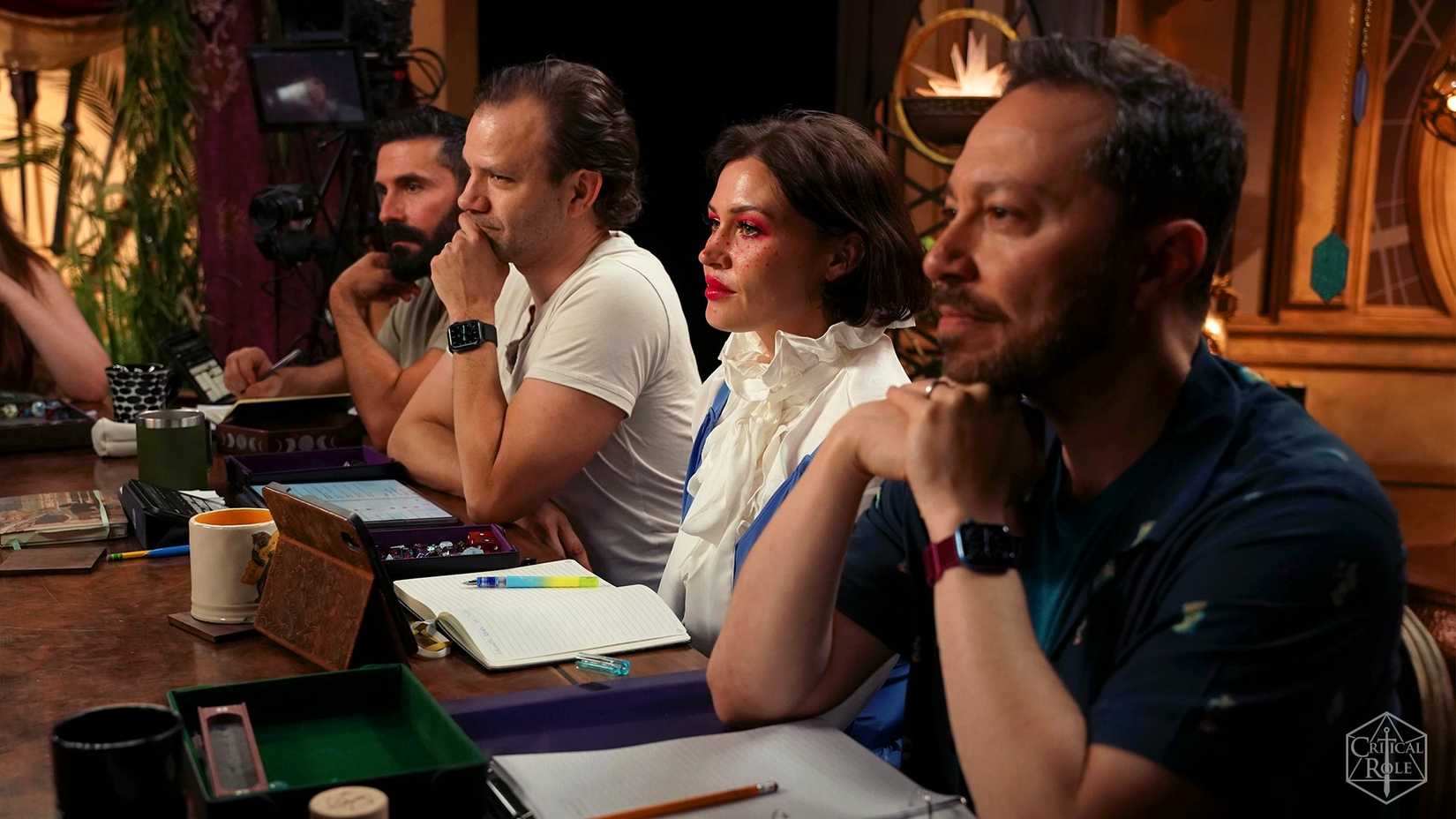 Imagem principal do elenco da campanha 4 da Critical Role. Apresenta Luis Carazo, Liam O'Brien, Whitney Moore e Sam Riegel sentados a uma mesa.