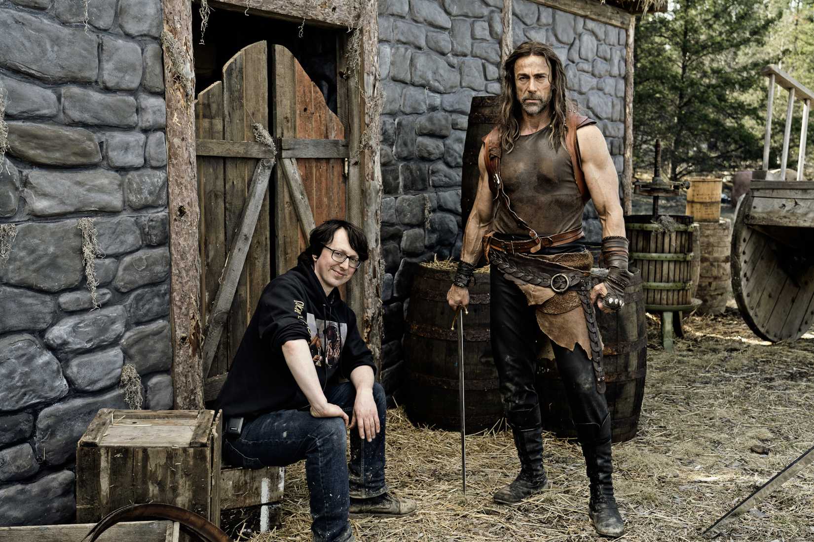Steven Kostanski, do Deathstalker, sentado ao lado de Daniel Bernhardt em sua fantasia de guerreiro no conjunto medieval de Deathstalker
