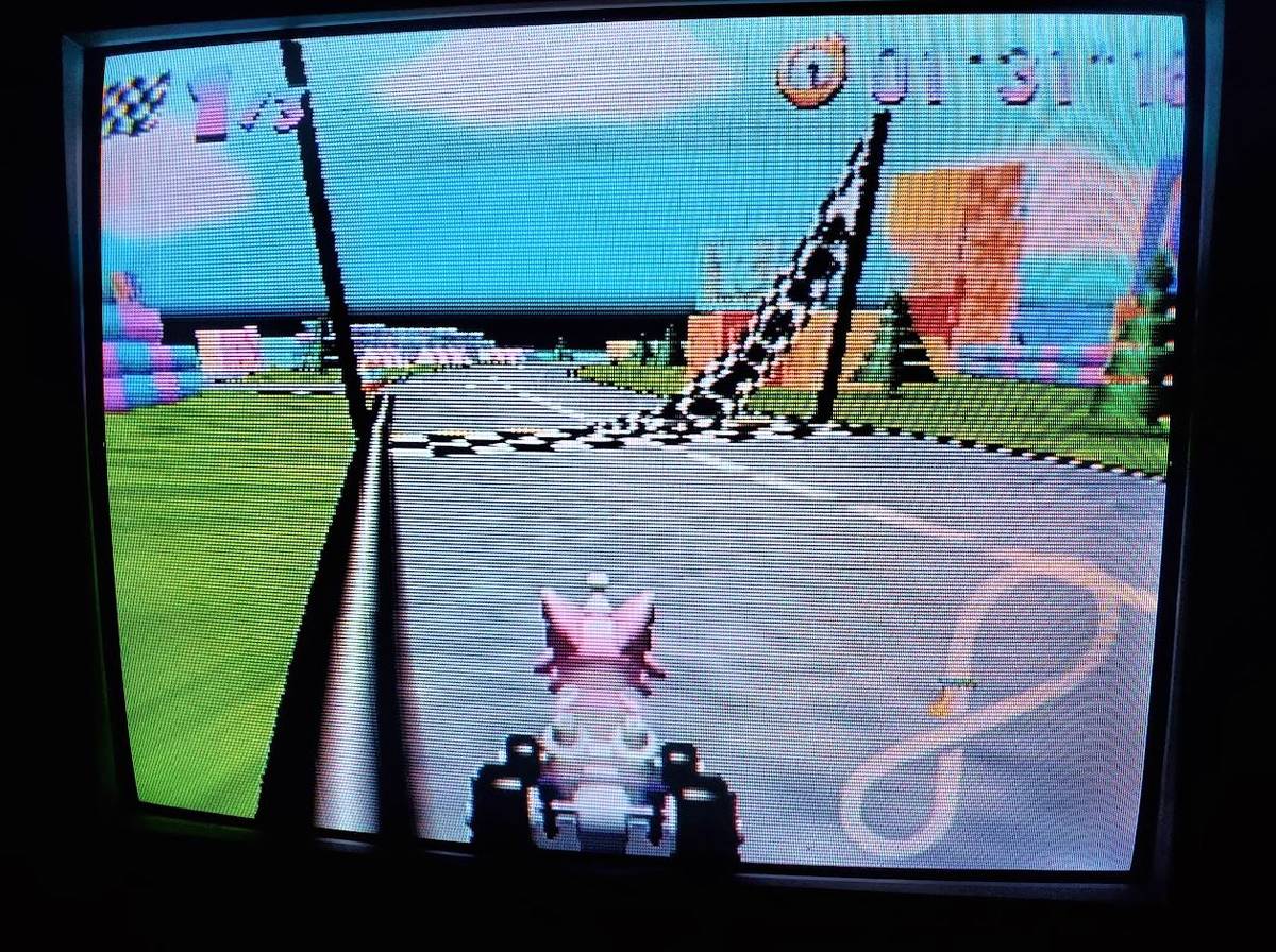 Um CRT exibe imagens do Kitty Kart 64, um jogo de corrida de terror onde tudo está errado. 