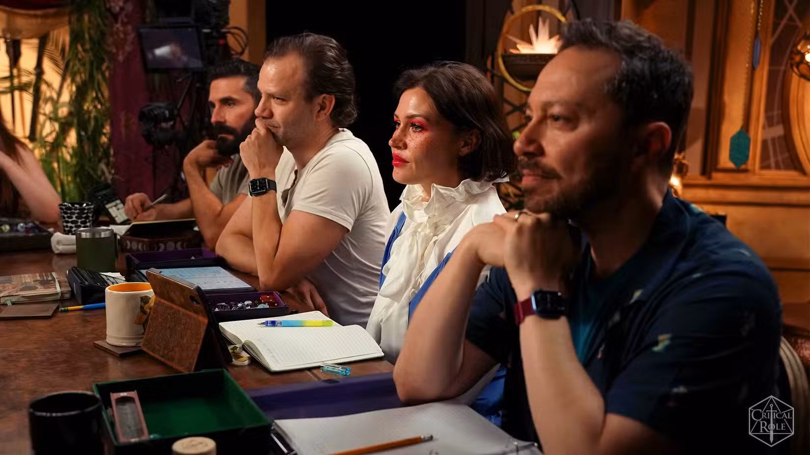 Imagem principal do elenco da campanha 4 da Critical Role. Apresenta Luis Carazo, Liam O'Brien, Whitney Moore e Sam Riegel sentados a uma mesa.