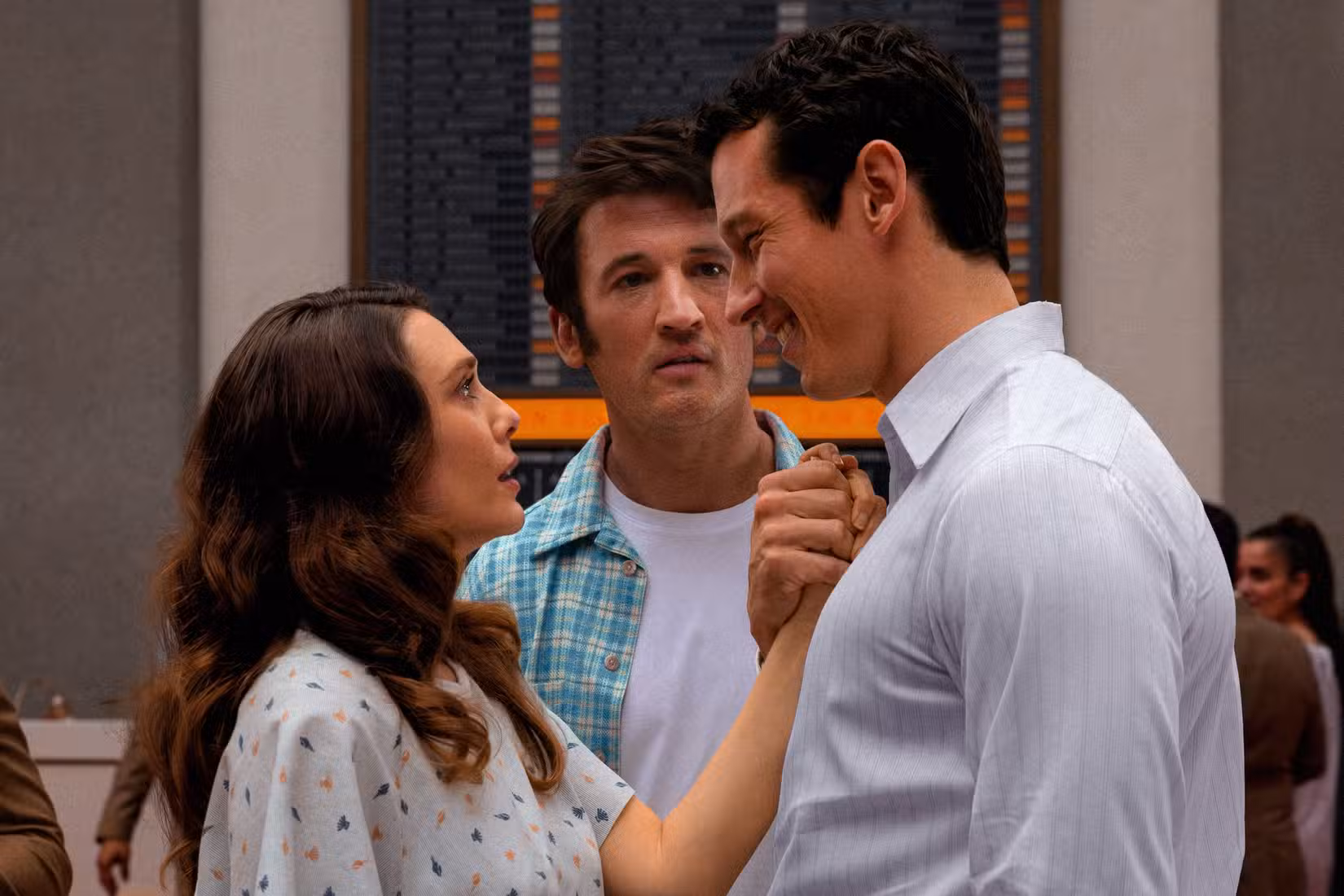 Luke (Callum Turner) e Joan (Elizabeth Olsen) sorriem romanticamente um para o outro e ficam próximos enquanto Larry (Miles Teller) tenta ficar entre eles na Eternidade.