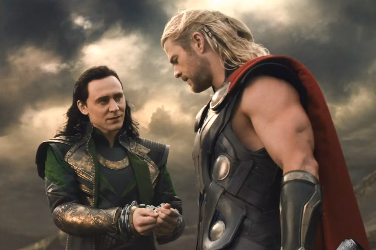 Tom Hiddleston como Loki mostra seus pulsos amarrados para Chris Hemsworth como Thor em Thor: The Dark World