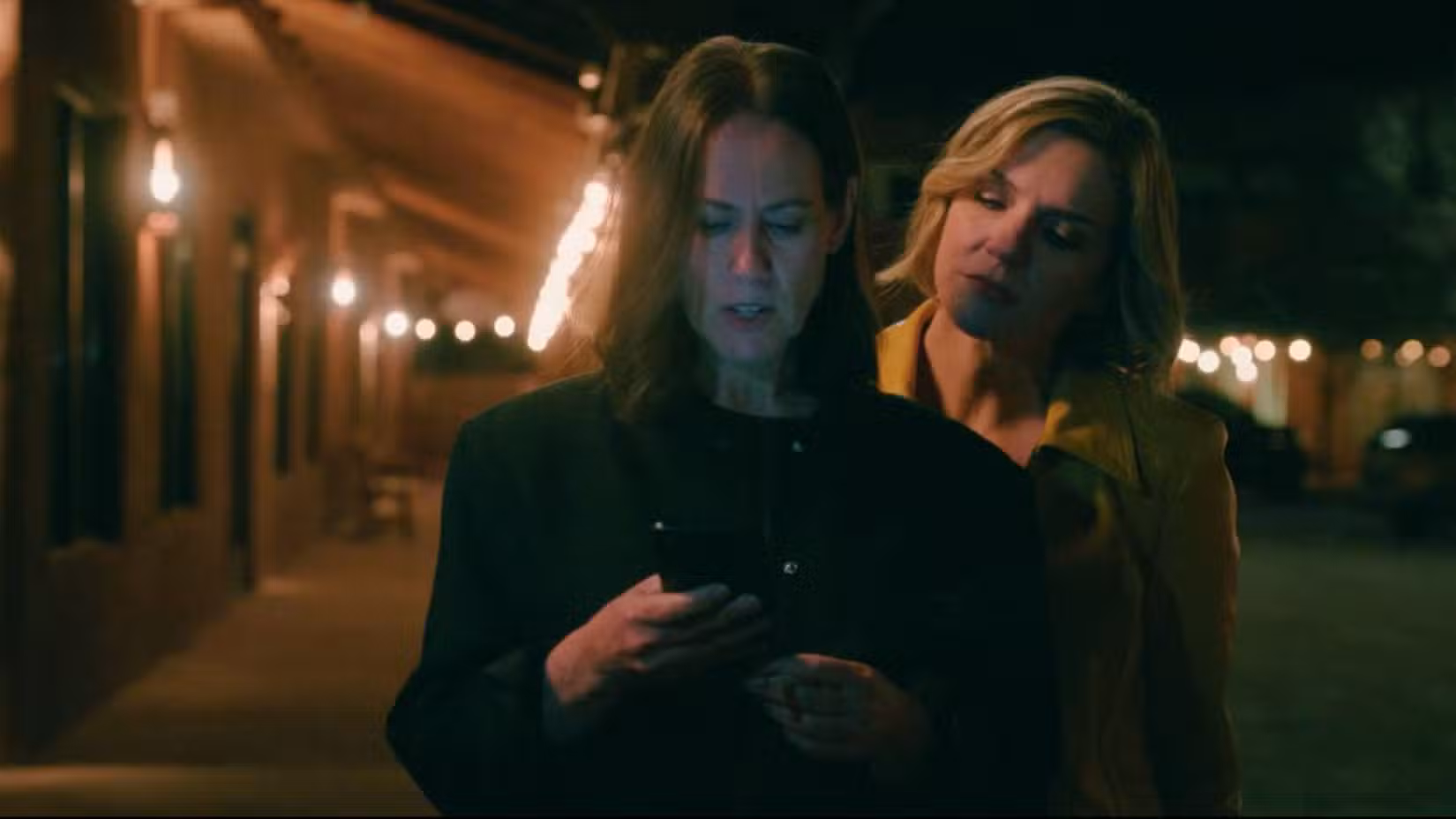 Miriam Shor como Helen e Rhea Seehorn como Carol Sturka. Os dois estão em um estacionamento iluminado por luzes. Carol olha por cima do ombro de Helen para o telefone na mão de Helen.