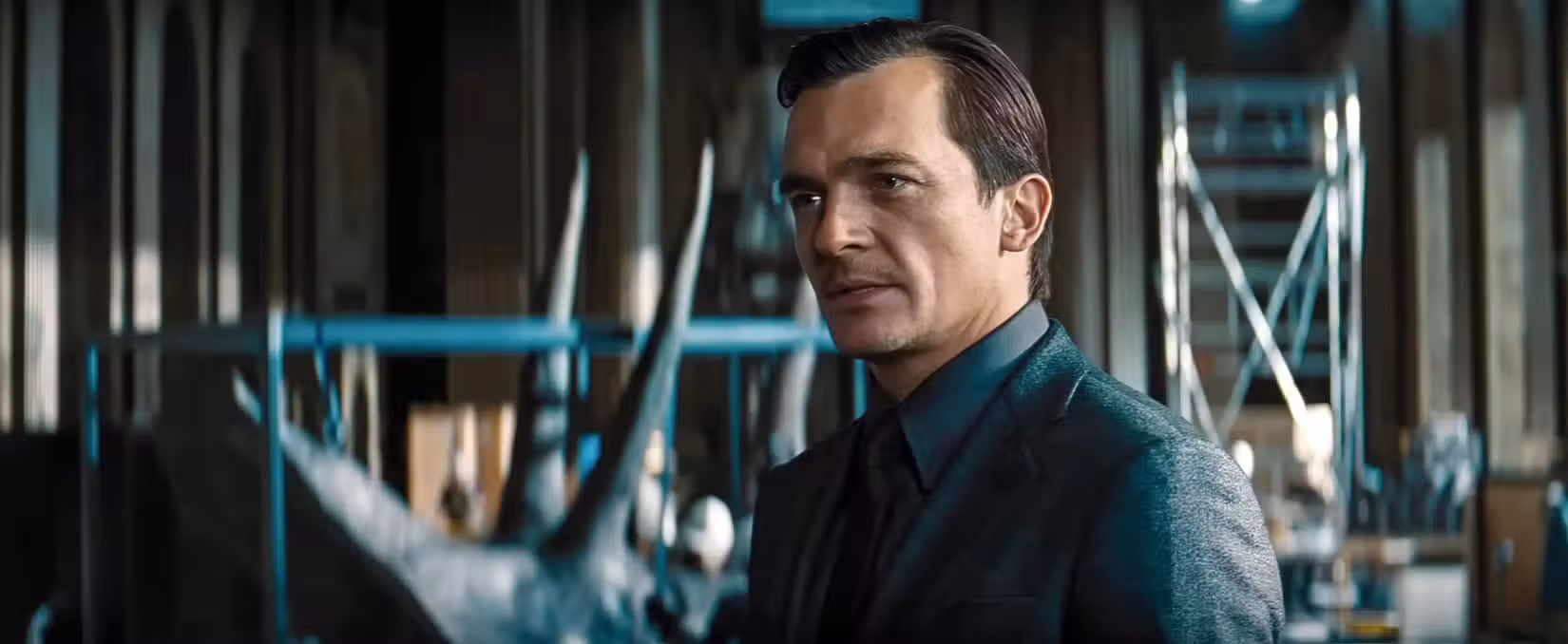 Rupert Friend como Martin Krebs, um farmacêutico desprezível e bem vestido, em Jurassic World Rebirth