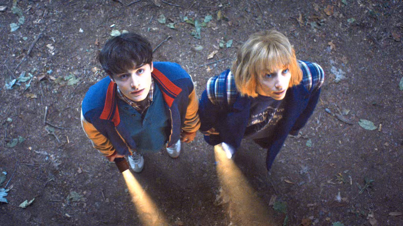 Noah Schnapp como Will Byers e Maya Hawke como Robin Buckley seguram lanternas na 5ª temporada de Stranger Things