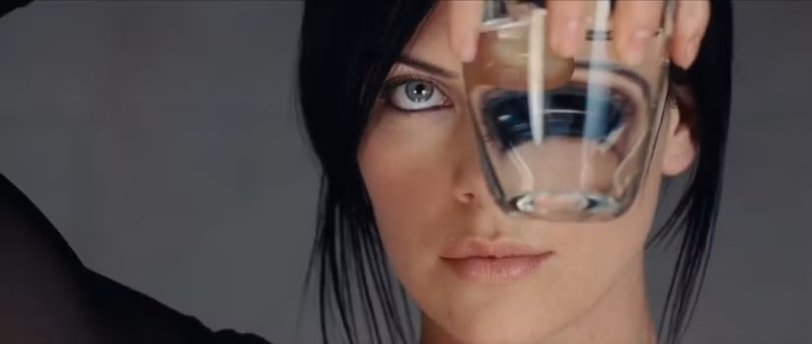Em uma cena do filme de ficção científica Aeon Flux, a personagem-título de Charlize Theron examina um copo com líquido, cujo reflexo distorce a imagem de um de seus olhos
