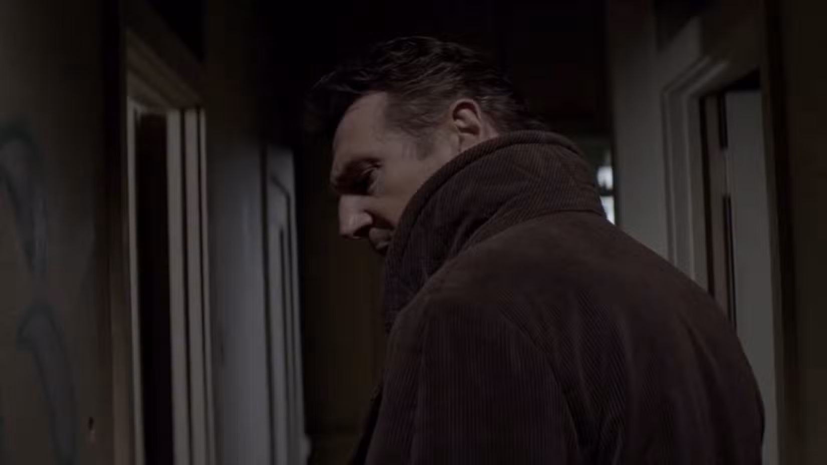 Liam Neeson se escondendo por um corredor em uma cena do filme A Walk Among the Tombstones