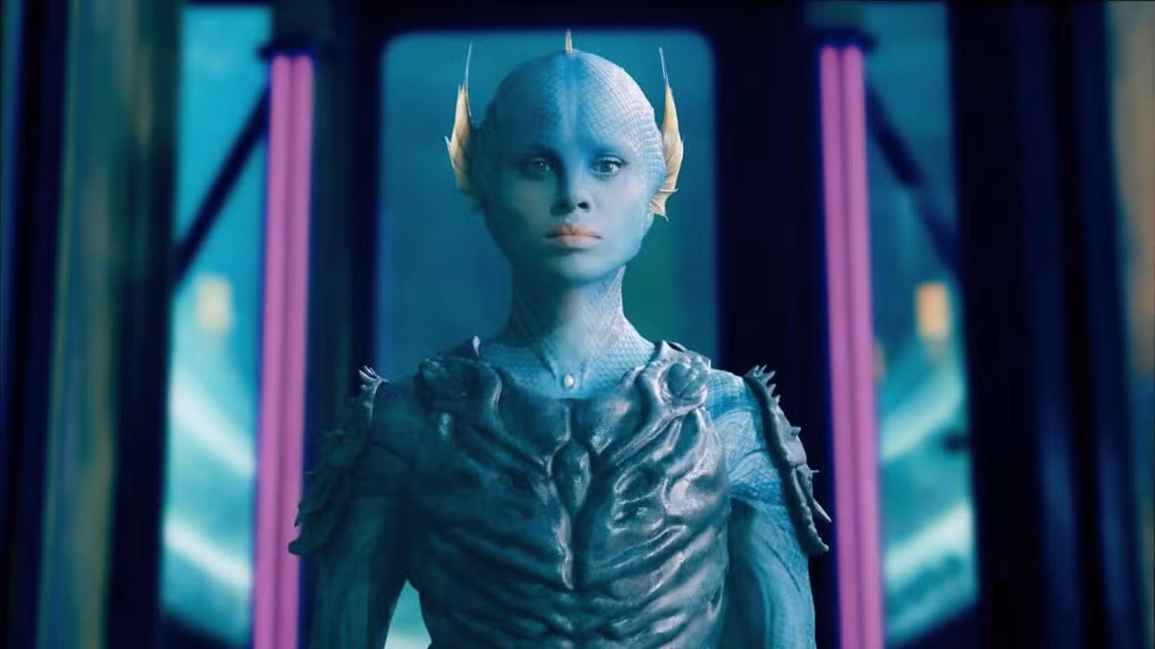 Gugu Mbatha-Raw interpreta Salt em A Guerra entre a Terra e o Mar. Ela é uma pessoa de pele azul, peixe, que olha para frente cercada por uma nave alienígena.