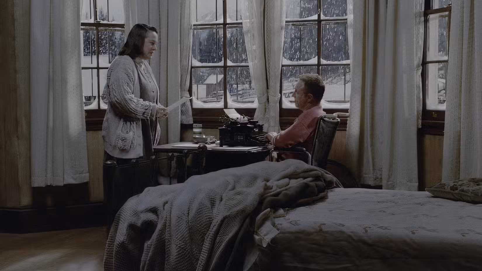 E Paul, ferido, fica sentado diante de sua máquina de escrever enquanto Annie lê seu último rascunho.