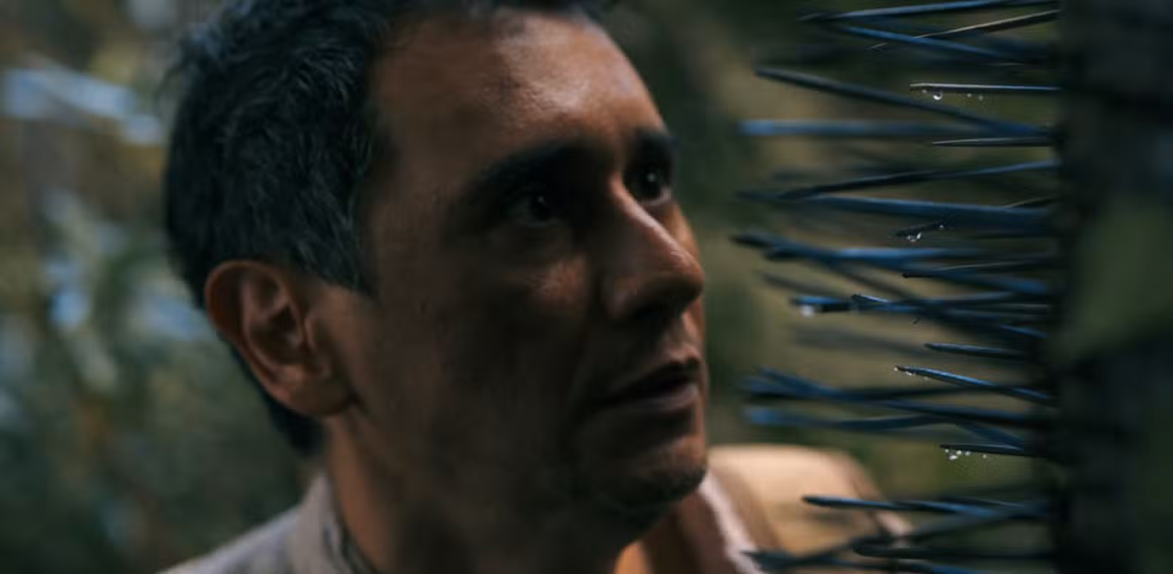 Manousos (Carlos-Manuel Vesga) CHORRIFICADO ao olhar para os espiões salientes de um chunga pluribus