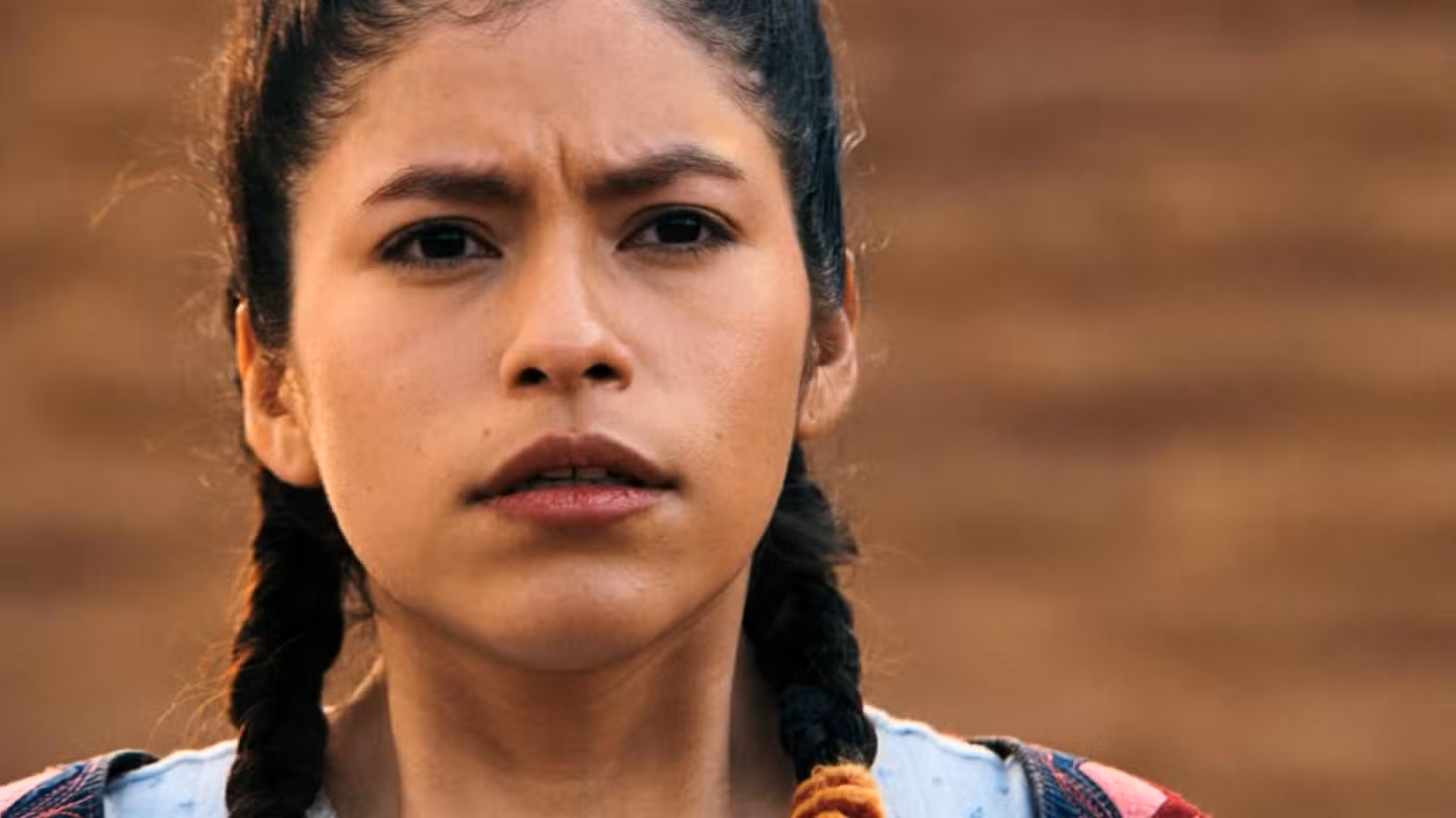 Uma captura de tela de Kusimayu (Darinka Arones) do final do Pluribus. Ela olha para frente, com os olhos estreitados e o queixo ligeiramente caído.