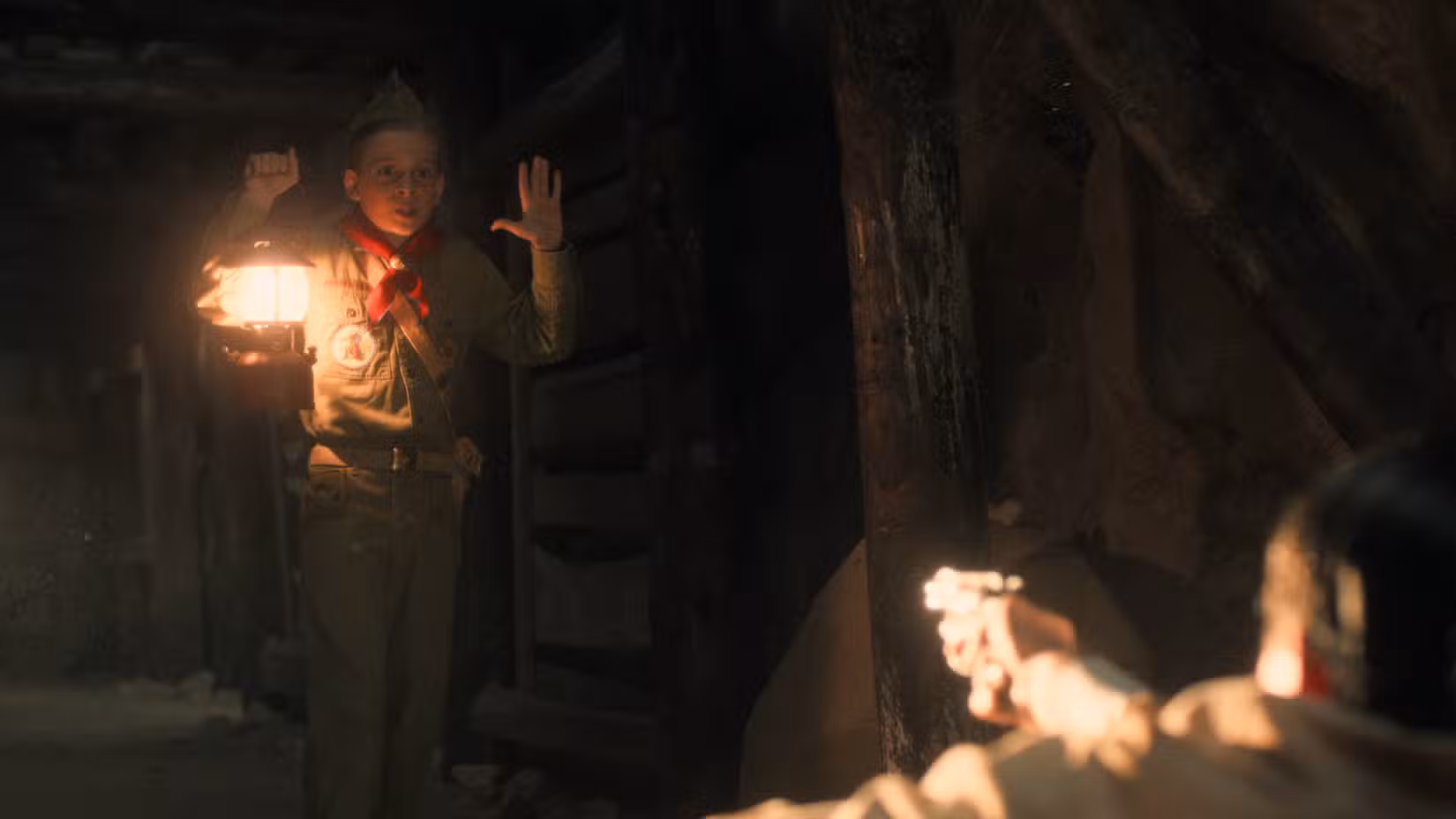 Um jovem Henry Creel (Maksim Blatt) levanta as mãos enquanto um homem em um poço de mina em Nevada aponta uma arma para ele na 5ª temporada de Stranger Things, episódio 6