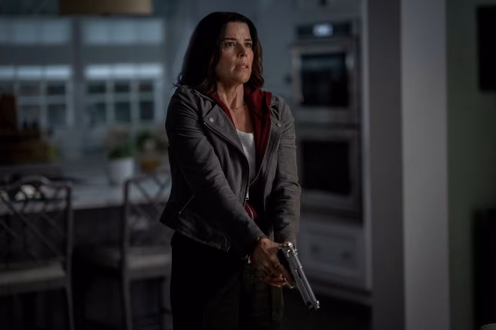 Sidney, de Neve Campbell, segura uma pistola em guarda em Pânico 7