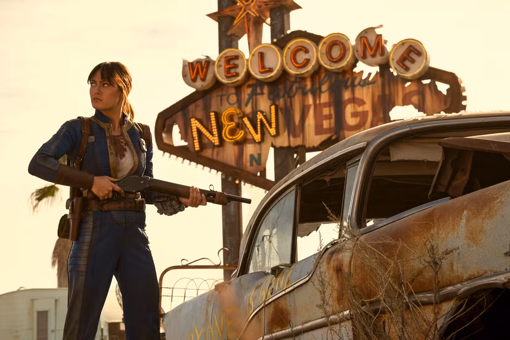 Lucy parada na frente do "Bem-vindo a Nova Vegas" entre na 2ª temporada de Fallout.