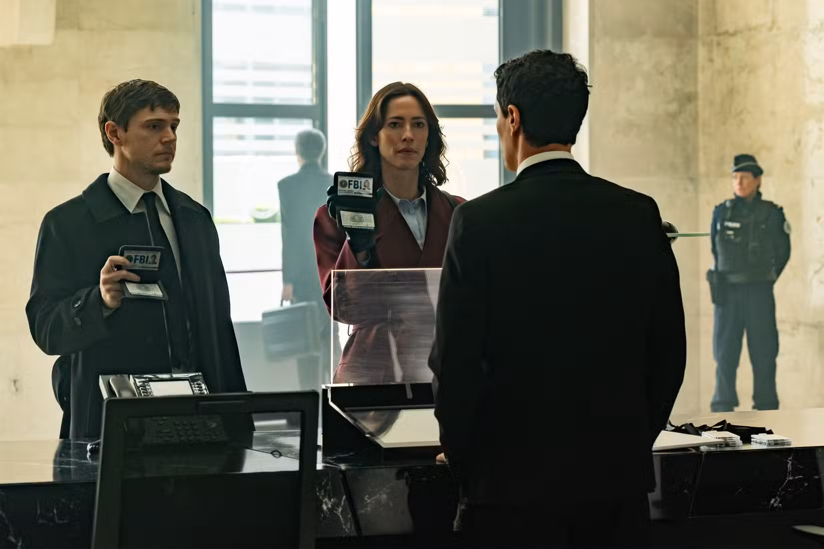 Os agentes do FBI Cooper e Jordan (Evan Peters e Rebecca Hall) mostram suas identidades em um balcão de segurança em uma imagem de imprensa chocantemente mundana do programa de TV bastante sinistro The Beauty