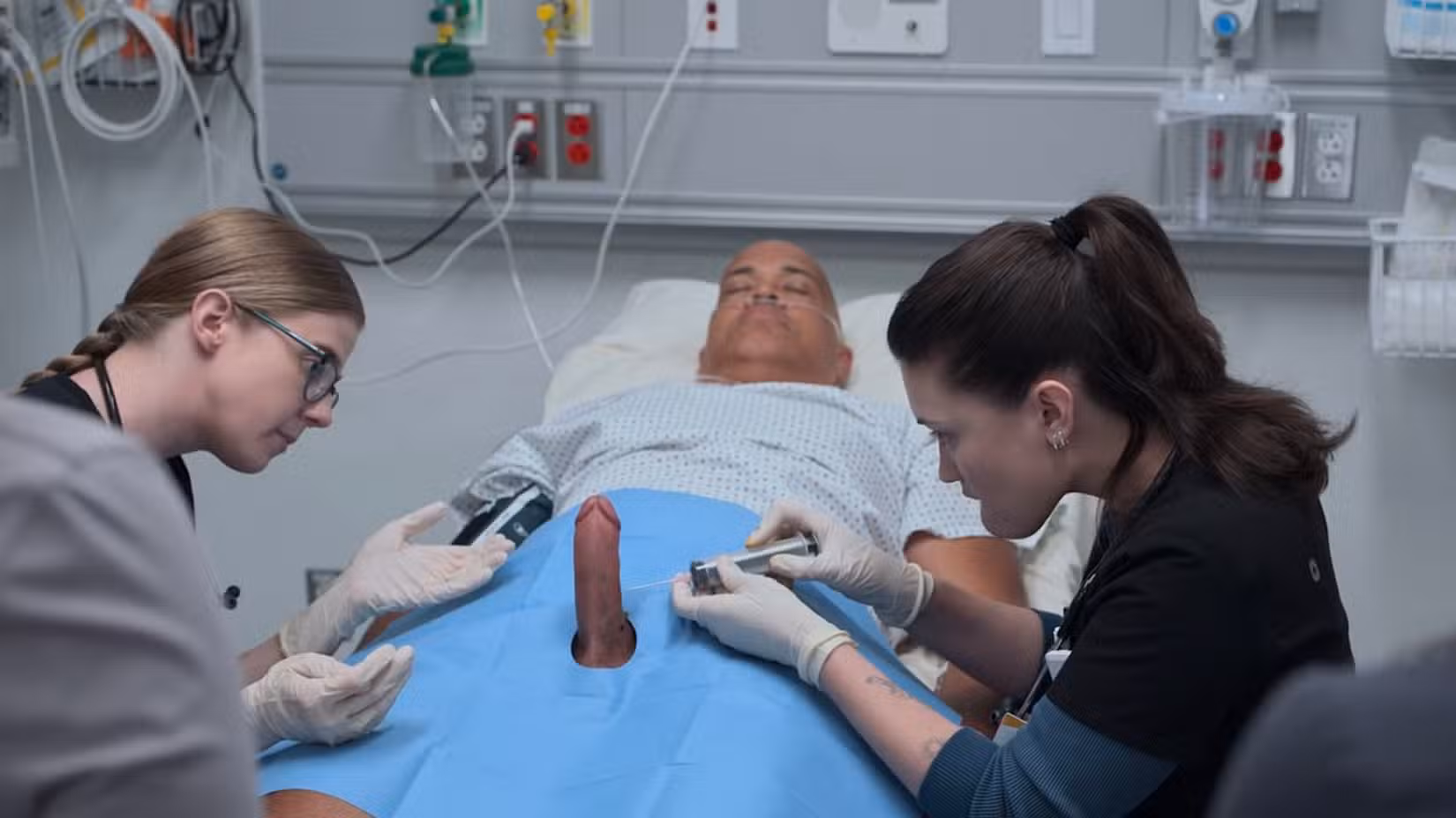 Mel King (Taylor Dearden) e Dra. Trinity Santos (Isa Briones) usam uma seringa para drenar sangue do pênis ereto de um paciente (Christopher T. Wood)