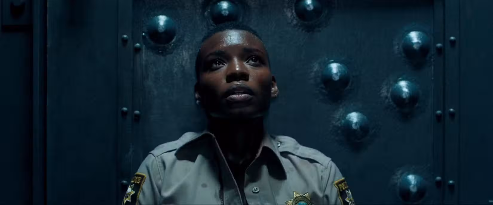 Alexis Louder se apoia em uma porta à prova de balas em close em uma cena tensa de Copshop (2021)