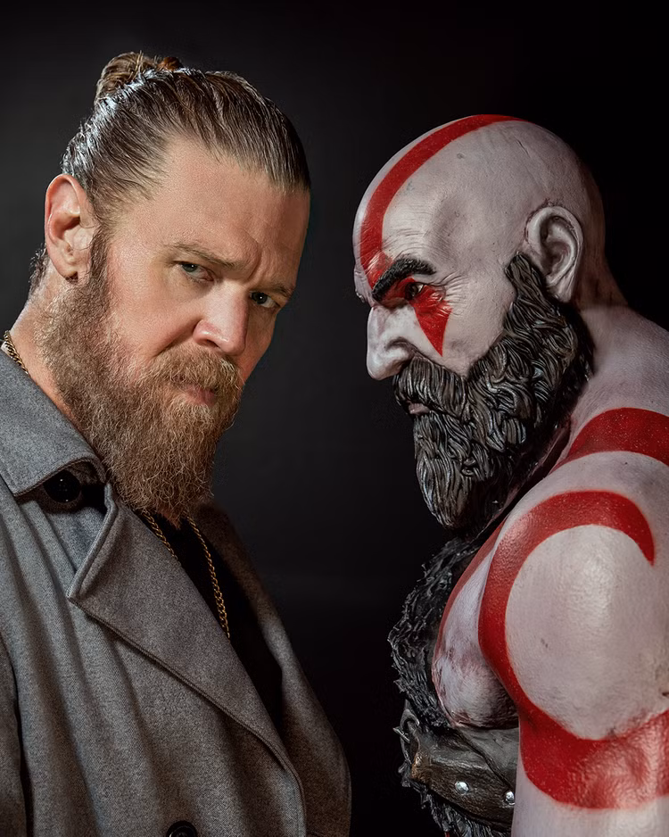 O ator Ryan Hurst ao lado de uma estátua de Kratos de God of War