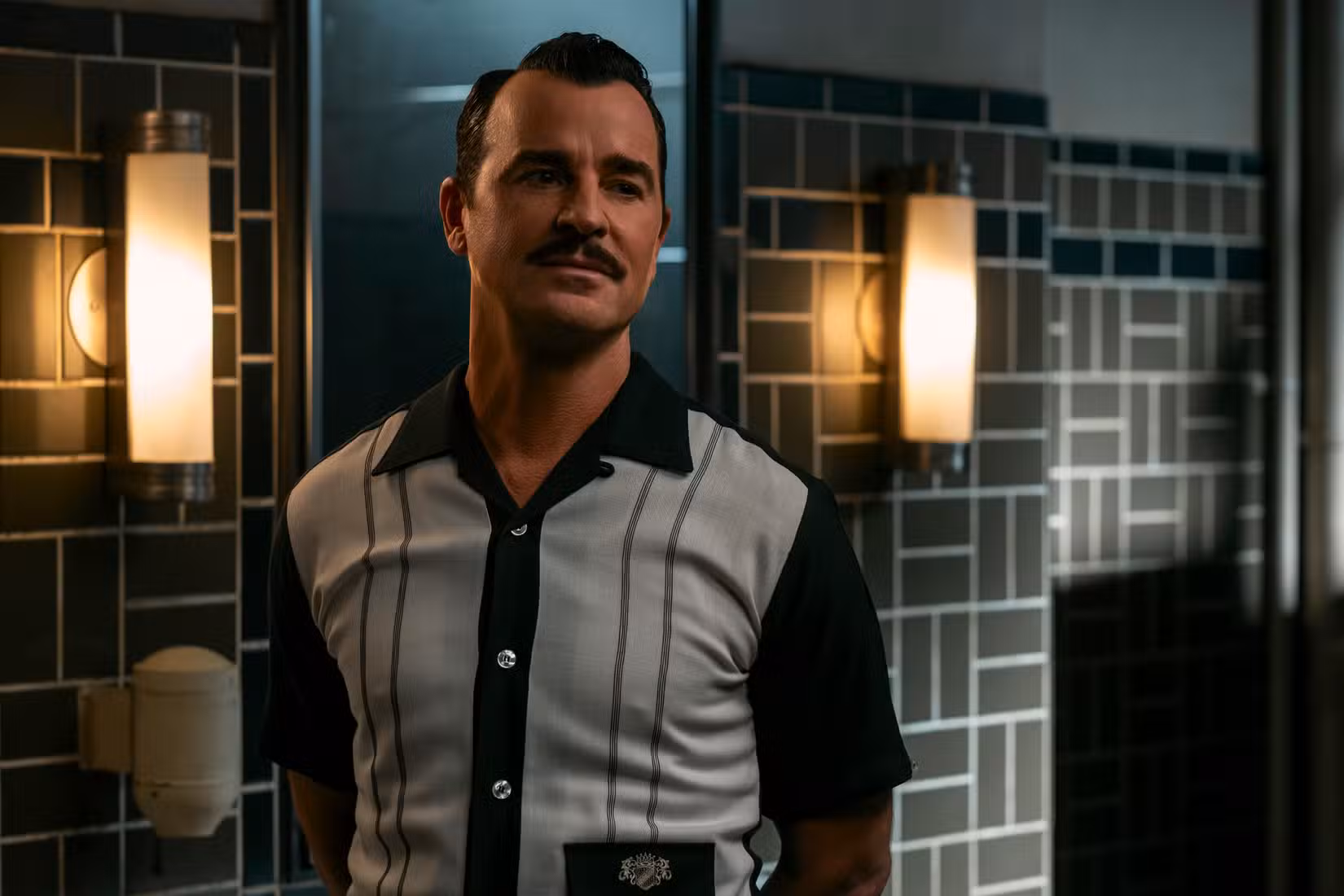 House (Justin Theroux) aborda Cooper Howard em um banheiro público sem revelar sua identidade em Fallout.