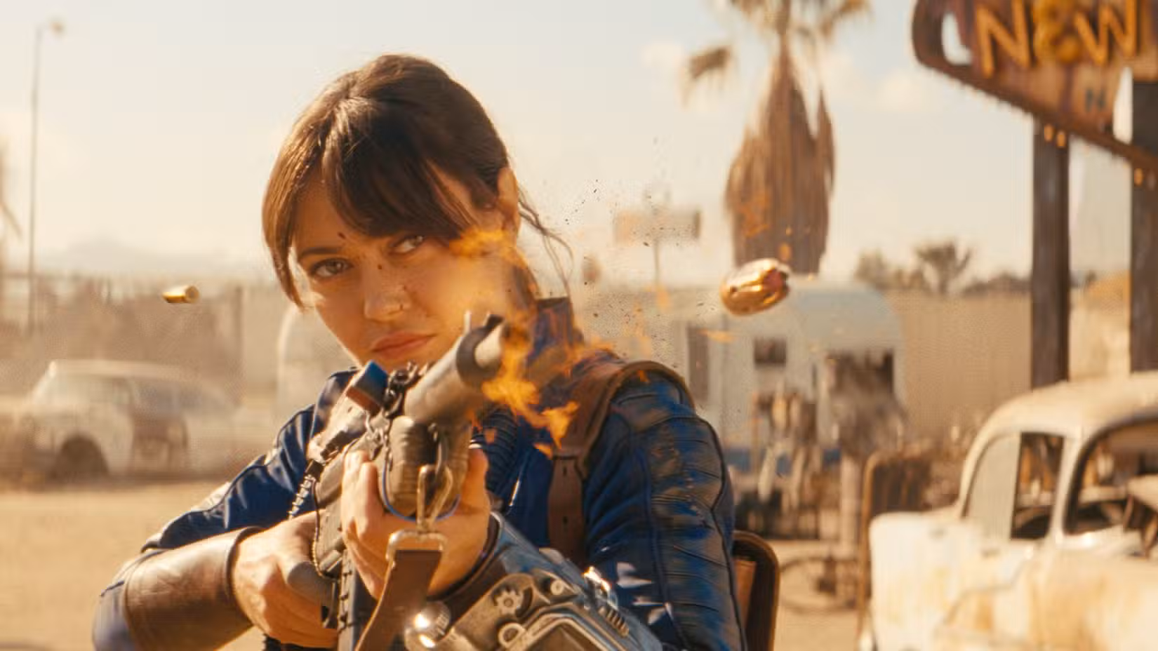 Lucy (Ella Purnell) dispara uma arma em frente à placa de New Vegas na 2ª temporada de Fallout