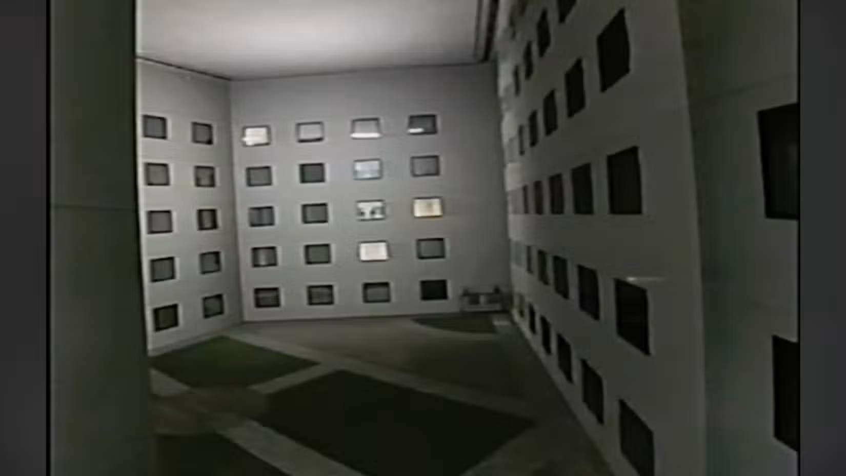 Uma foto de um estranho pátio de hotel com grama no chão, mas um teto onde deveria haver céu.