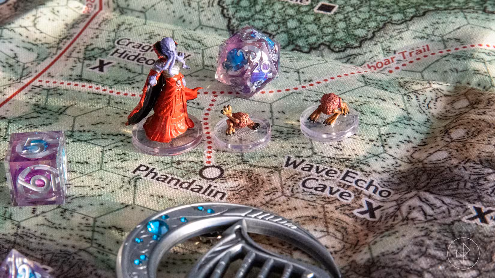 Um mapa de tela da região da Costa da Espada com miniaturas de Dungeons and Dragons e dados em cima dele.