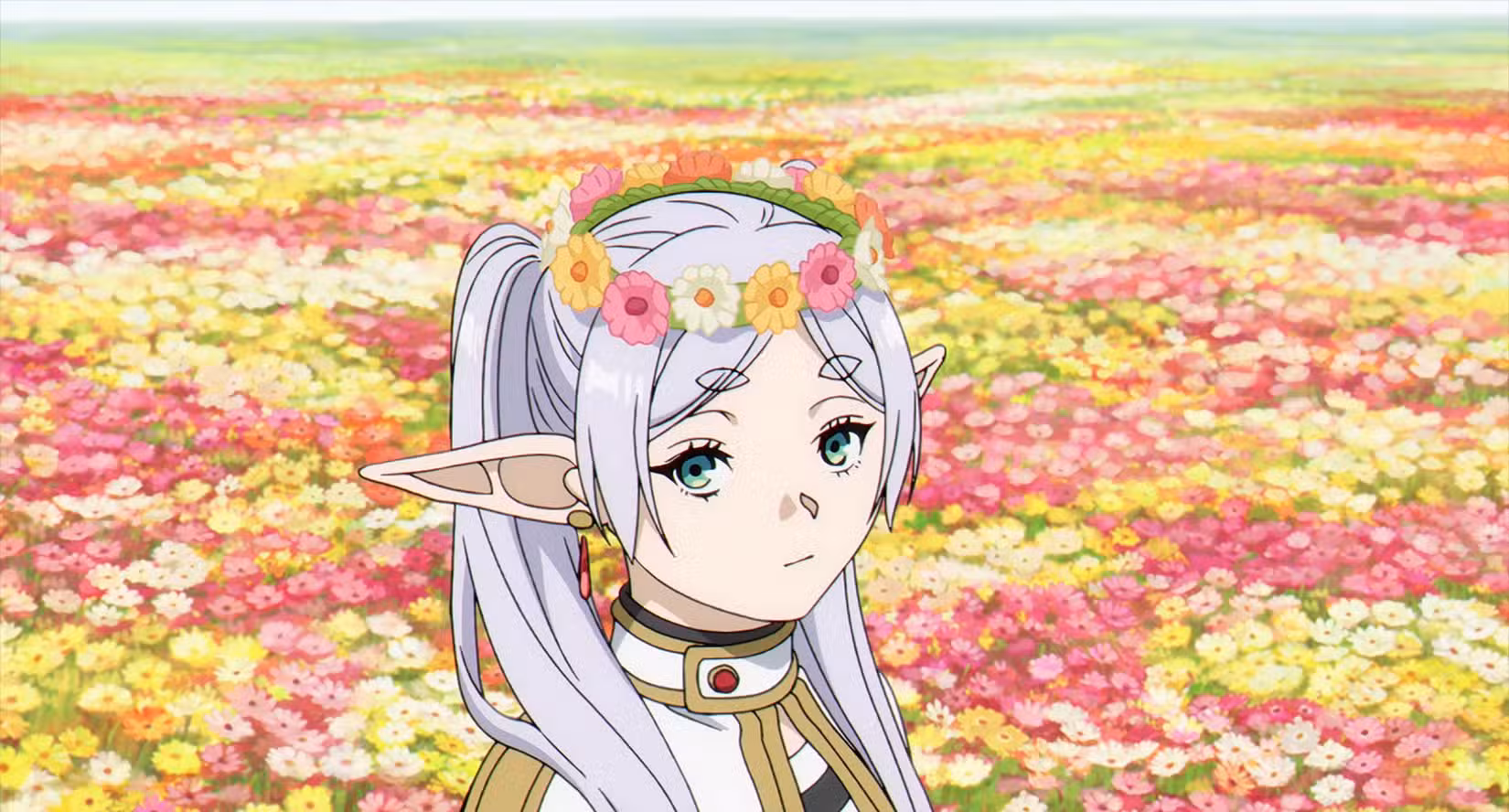 Frieren, uma elfa de cabelos prateados, parada em um campo de flores com uma coroa de flores na cabeça em Frieren: Beyond Journey's End.