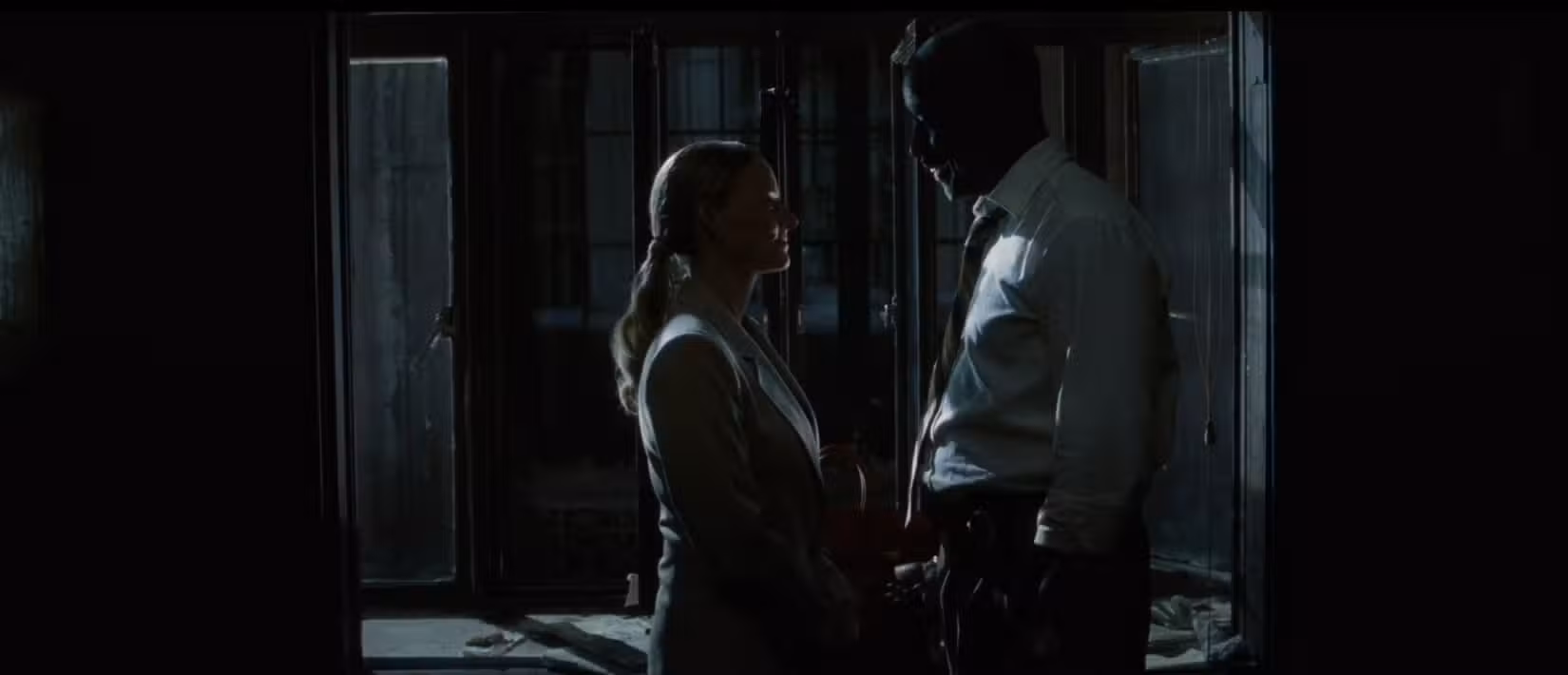 Uma imagem noir e sombria de Denzel Washington e Jodie Foster se enfrentando em uma discussão tensa, filmada de média distância, em uma cena do filme Inside Man, de Spike Lee